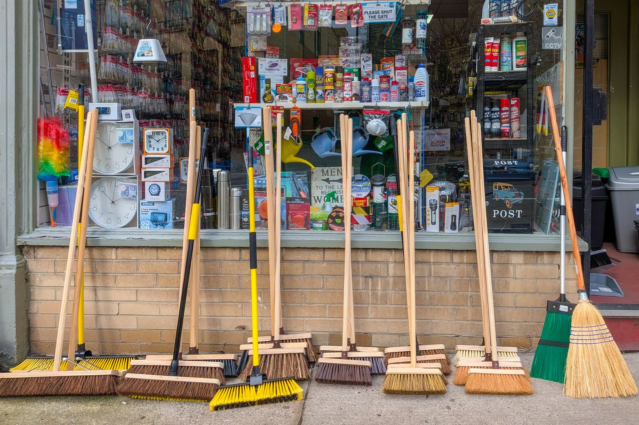 A variety of brooms displayed outside a hardware store in Harrogate, England.