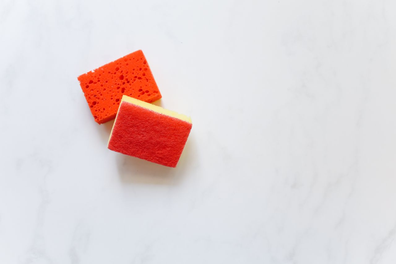 services-01 Two bright orange sponges suitable for cleaning against a white background.